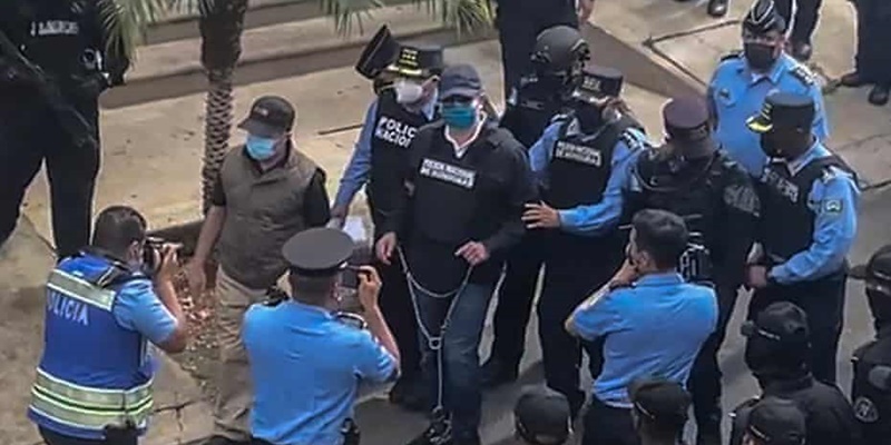 Mantan presiden Honduras Juan Orlando Hernández diborgol saat polisi membawanya keluar dari rumahnya pada Selasa (15/2)/Net