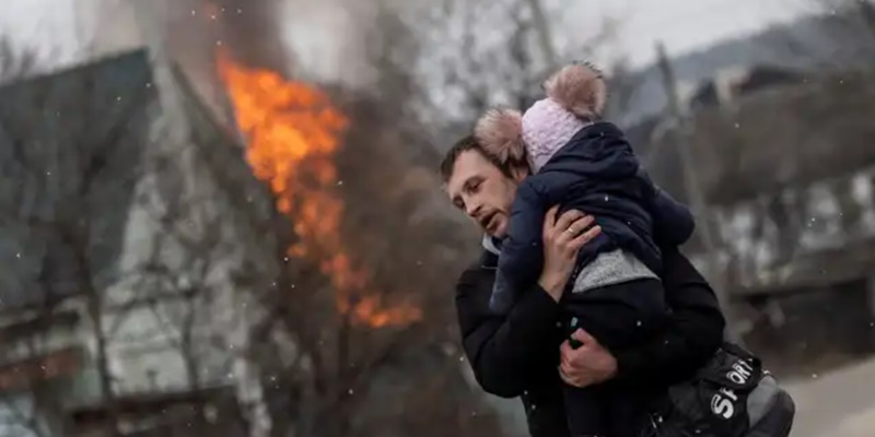 Seorang warga di Irpin membawa anaknya di tengah serangan Rusia/Net