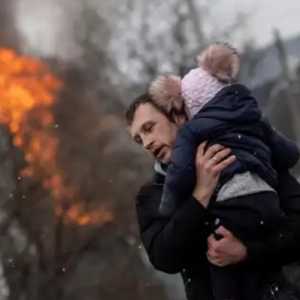 Seorang warga di Irpin membawa anaknya di tengah serangan Rusia/Net